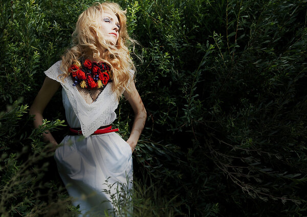 Довольно нежные светлые волосы женщина над зелеными кустами позирует
