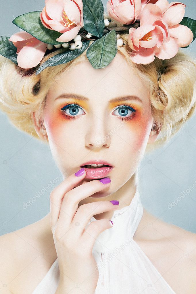 Lovely blonde super model in wreath of flowers and bright makeup