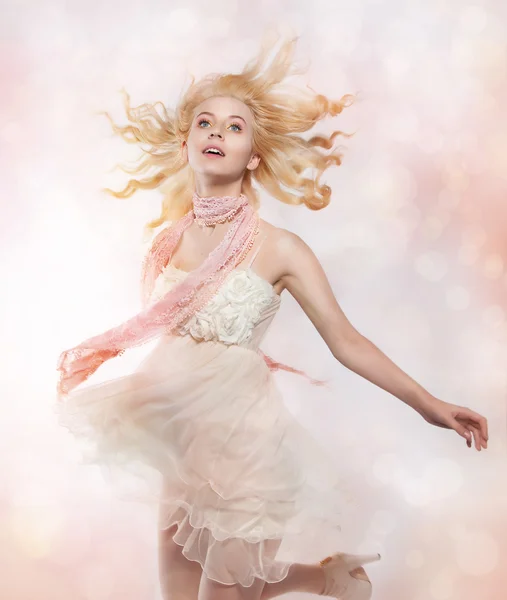 Linda menina artística cabelo loiro voando sobre fundo rosa — Fotografia de Stock