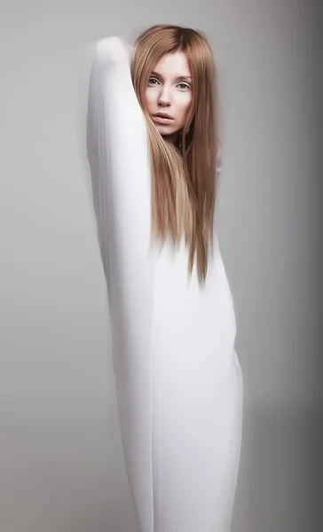 Luftiga ung flicka i vita kläder poserar i studio — Stockfoto