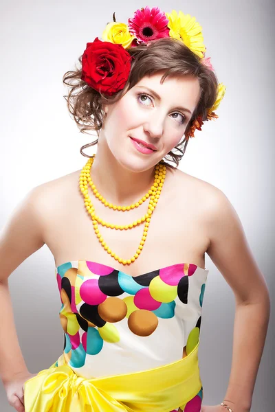 Çiçek ile poz parlak renkli elbiseli genç ve güzel kadın — Stok fotoğraf