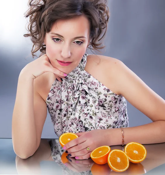 Schönes junges Mädchen mit frischen Orangenhälften sitzend — Stockfoto