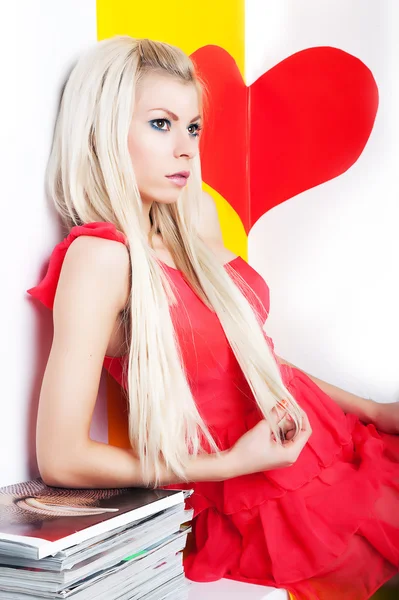 Sexy jovem loira posando em estúdio sobre coração vermelho — Fotografia de Stock