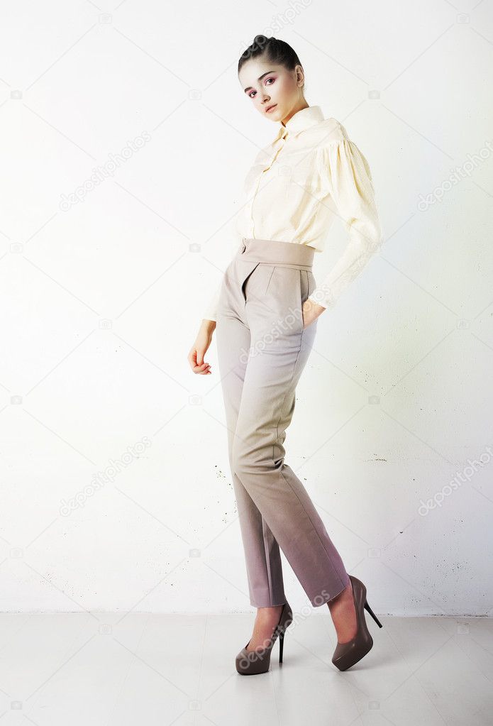 Pretty stylish girl in white trousers and blouse posing
