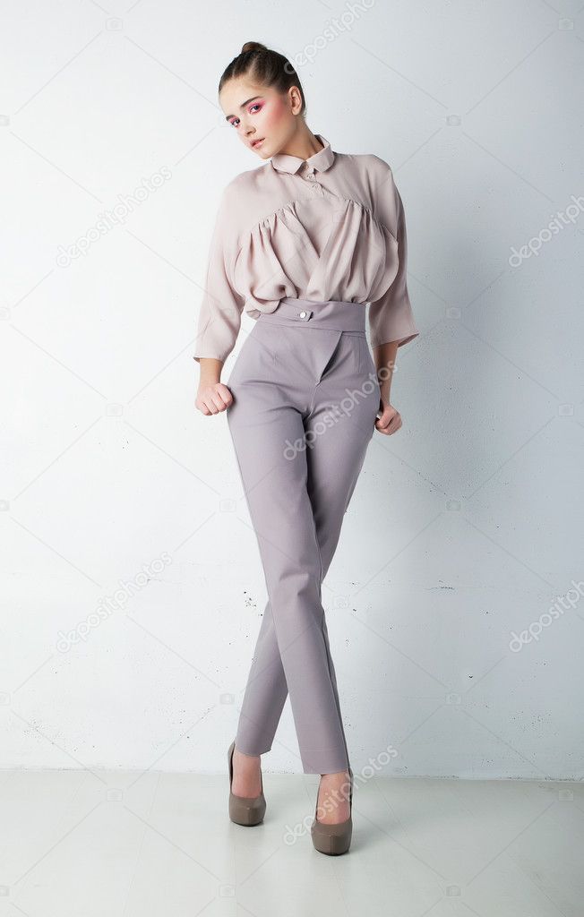 Fashionable young woman in trousers and shirt posing