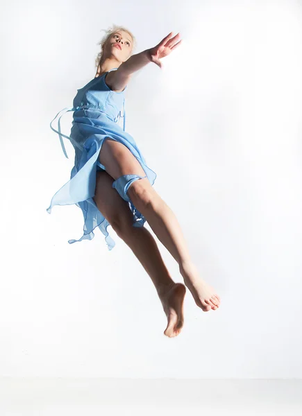 Lovely flying girl blonde in cyan dress. Studio shot — Stock Photo, Image