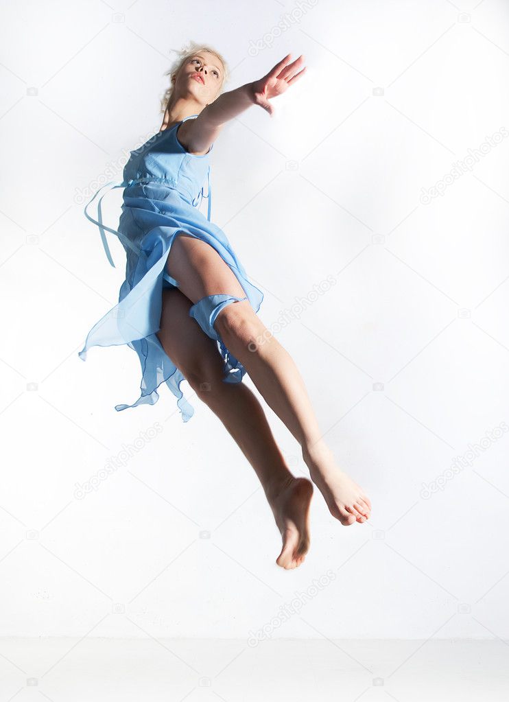 Lovely flying girl blonde in cyan dress. Studio shot