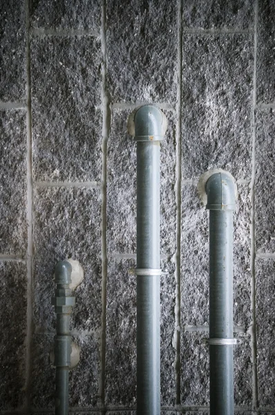 Rohre gegen grunzige Steinmauer — Stockfoto