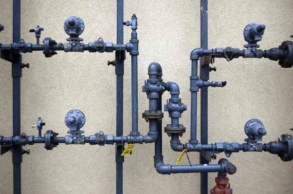 Трубы водопроводные на грубой стене — стоковое фото