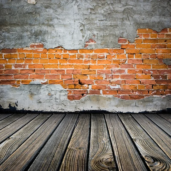 Room with stucco peeling brick wall and wooden floor — Stock Photo, Image