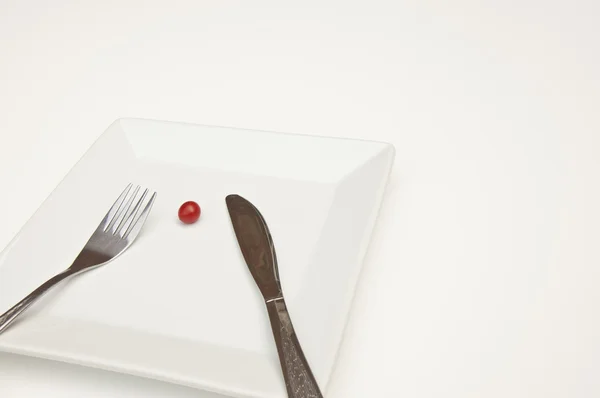 stock image Single tomato on a plate with knife & fork