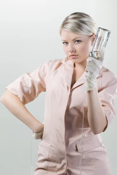 Jovem enfermeira com um conta-gotas na mão sobre fundo branco . — Fotografia de Stock