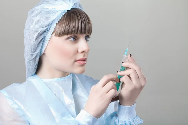 Jovem enfermeira usando uma máscara com um termômetro na mão — Fotografia de Stock