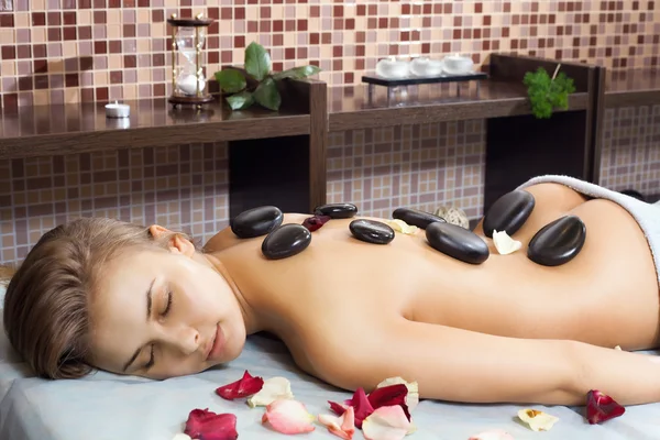 Mujer feliz recibiendo un masaje con piedra caliente en un centro de spa —  Fotos de Stock