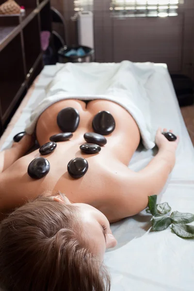 Mulher feliz recebendo uma massagem com pedra quente em um centro de spa — Fotografia de Stock