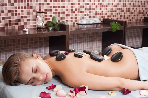 Frohe Frau, die eine Massage mit heißem Stein in einem Wellnesszentrum erhält — Stockfoto