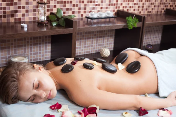 stock image Glad woman receiving a massage with hot stone in a spa center