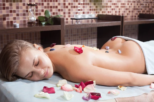 Glad woman receiving a massage with hot stone in a spa center — Stock Photo, Image