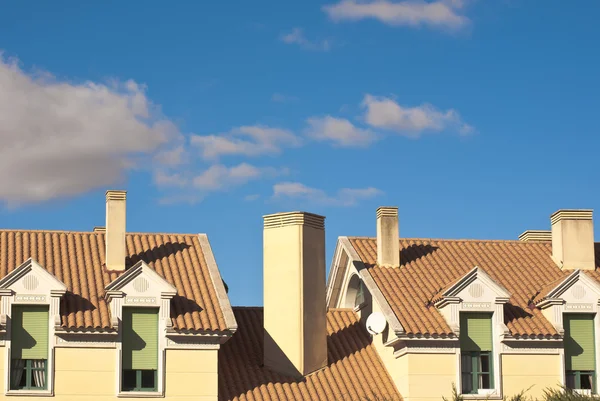 Gable takkupor och tak i bostadshus under en blå himmel Royaltyfria Stockfoton