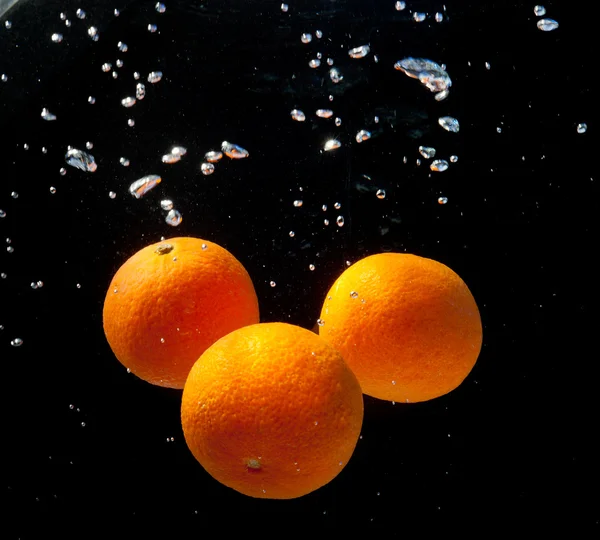 stock image Three oranges in water with bubbles