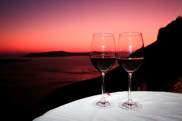 ギリシャのサントリーニ島の夕日の前で味の赤ワイン ロイヤリティフリーのストック画像