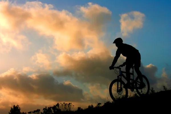 Горный велосипедист с облаками заката — стоковое фото