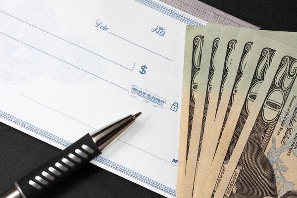 Blank check with twenty dollar bills at its side — Stock Photo, Image