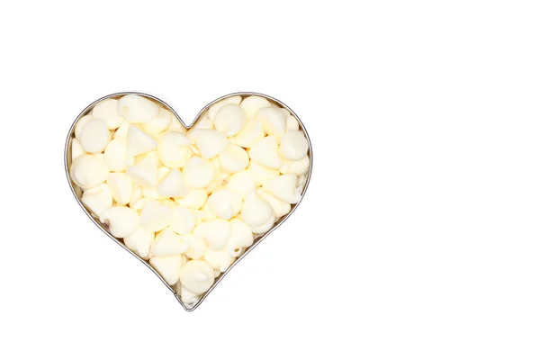 White chocolate morsels fill a silver heart — Stock Photo, Image