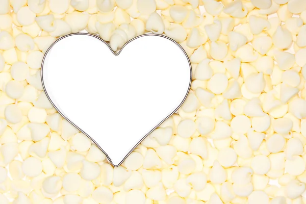 Witte chocolade stukjes omringen een zilveren hart — Stockfoto