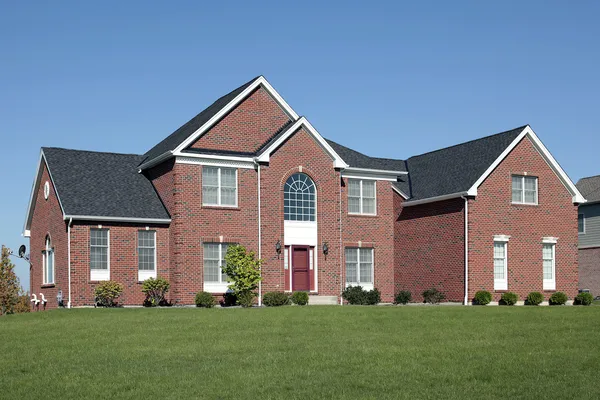 stock image Large brick home with red door