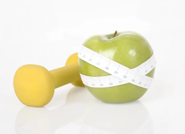Dumbbell, green apple and measure tape — Stock Photo, Image