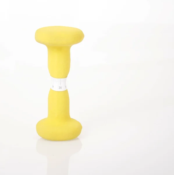 Yellow dumbbell and measure tape — Stock Photo, Image