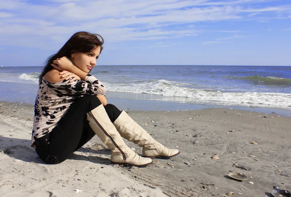 Jovem em botas de couro sentado na praia — Fotografia de Stock