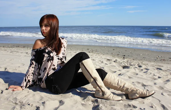Jovem em botas de couro sentado na praia — Fotografia de Stock