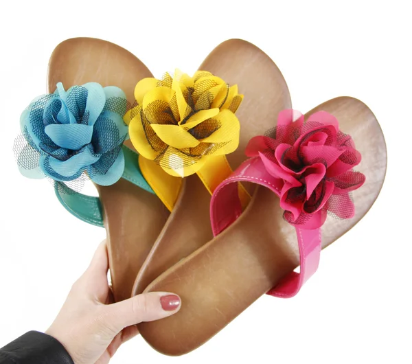 Chanclas de colores con flores en la mano — Foto de Stock