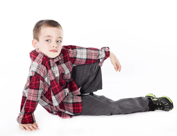 Young boy in plaid shirt laying on his side in studio — Stock Photo, Image