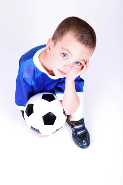Мальчик на коленях с футбольным мячом — стоковое фото