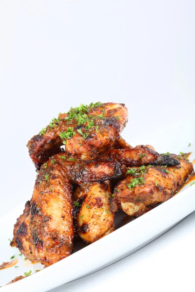 Ailes de poulet grillées chaudes sur une assiette blanche avec un filet de sauce — Photo