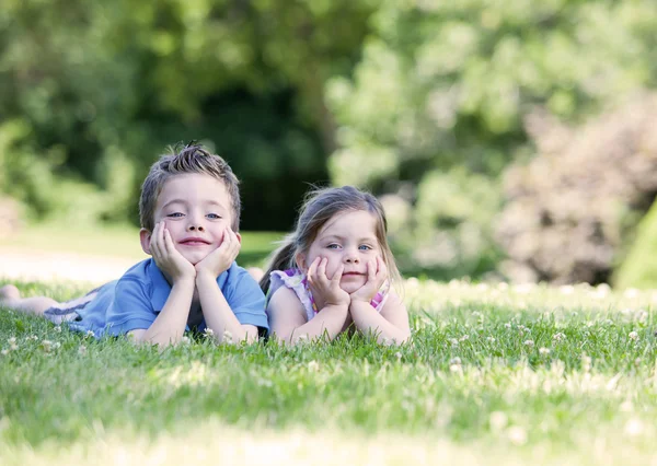 Siblings laying on the grass — Stock Photo, Image