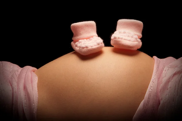 Розовые носки на беременном животе — стоковое фото