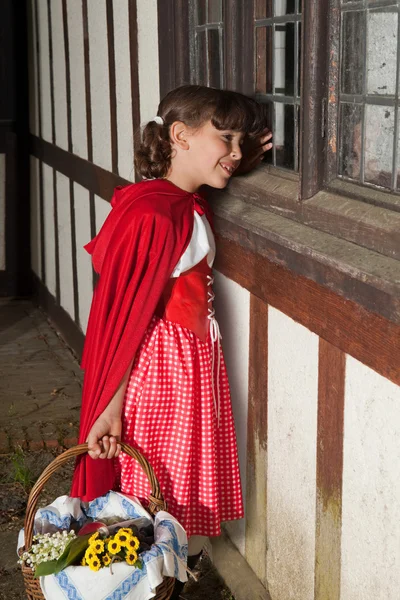 Красный капюшон у бабушкиного окна — стоковое фото