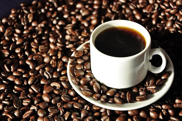stock image Coffee beans and a white cup of coffee on a saucer