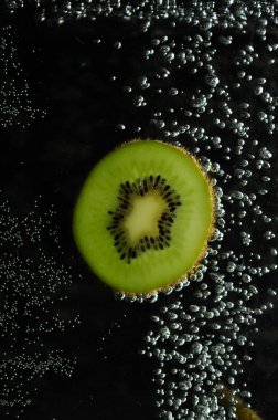 Kiwi and bubbles on a dark background.