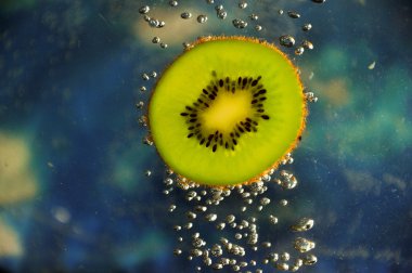 Kiwi with bubbles on blue background