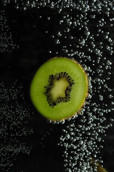 Stock image Kiwi and bubbles on a dark background.