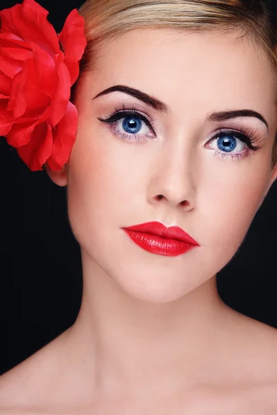 Jeune belle femme blonde avec rouge à lèvres rouge et fleur rouge dans ses cheveux — Photo