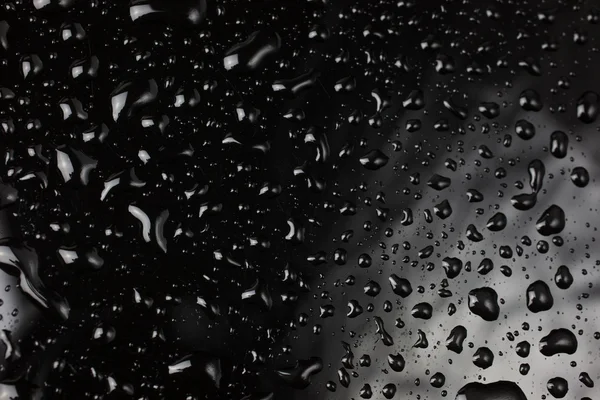 Wassertropfen auf glänzend schwarzer Oberfläche — Stockfoto