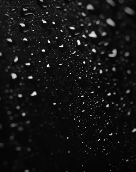 Extremo Close up de gotas de água na superfície preta — Fotografia de Stock