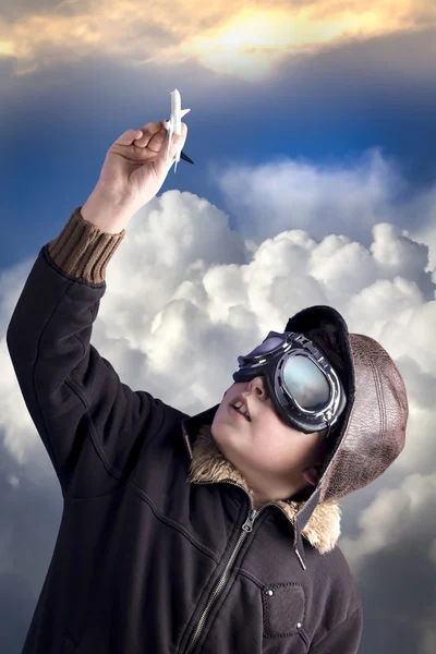 Boy as an old style pilot holding a toy airplane, heaven backgro — Stock Photo, Image