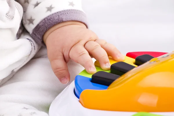Pequeno bebê mão pianista toca em um piano de brinquedo colorido — Fotografia de Stock